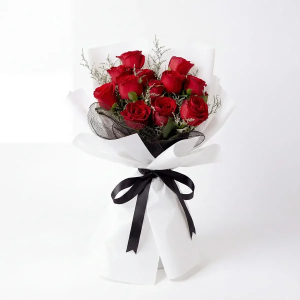 11 red roses bouquet white background Frontal shot of 11 premium red roses with white misty accents, wrapped in modern white paper with black mesh and ribbon.