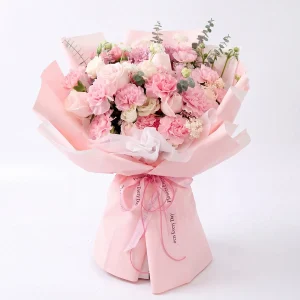 Frontal view of a sweet pink carnation and rose bouquet in soft pink layered wrapping. Perfect Mother's Day gift for China delivery.