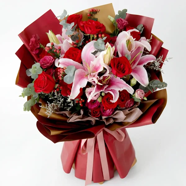 red rose lily bouquet top view Overhead view showing the rich density of blooming lilies, roses, and red berries with fresh eucalyptus leaves.