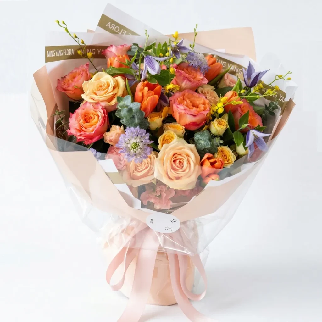 How to Send Flowers to China from Singapore An elegant garden-style bouquet featuring peach roses, vibrant tulips, and purple accents in soft pink wrapping. Luxury flower delivery in China.