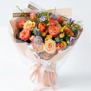 sunset glow peach rose tulip bouquet main An elegant garden-style bouquet featuring peach roses, vibrant tulips, and purple accents in soft pink wrapping. Luxury flower delivery in China.